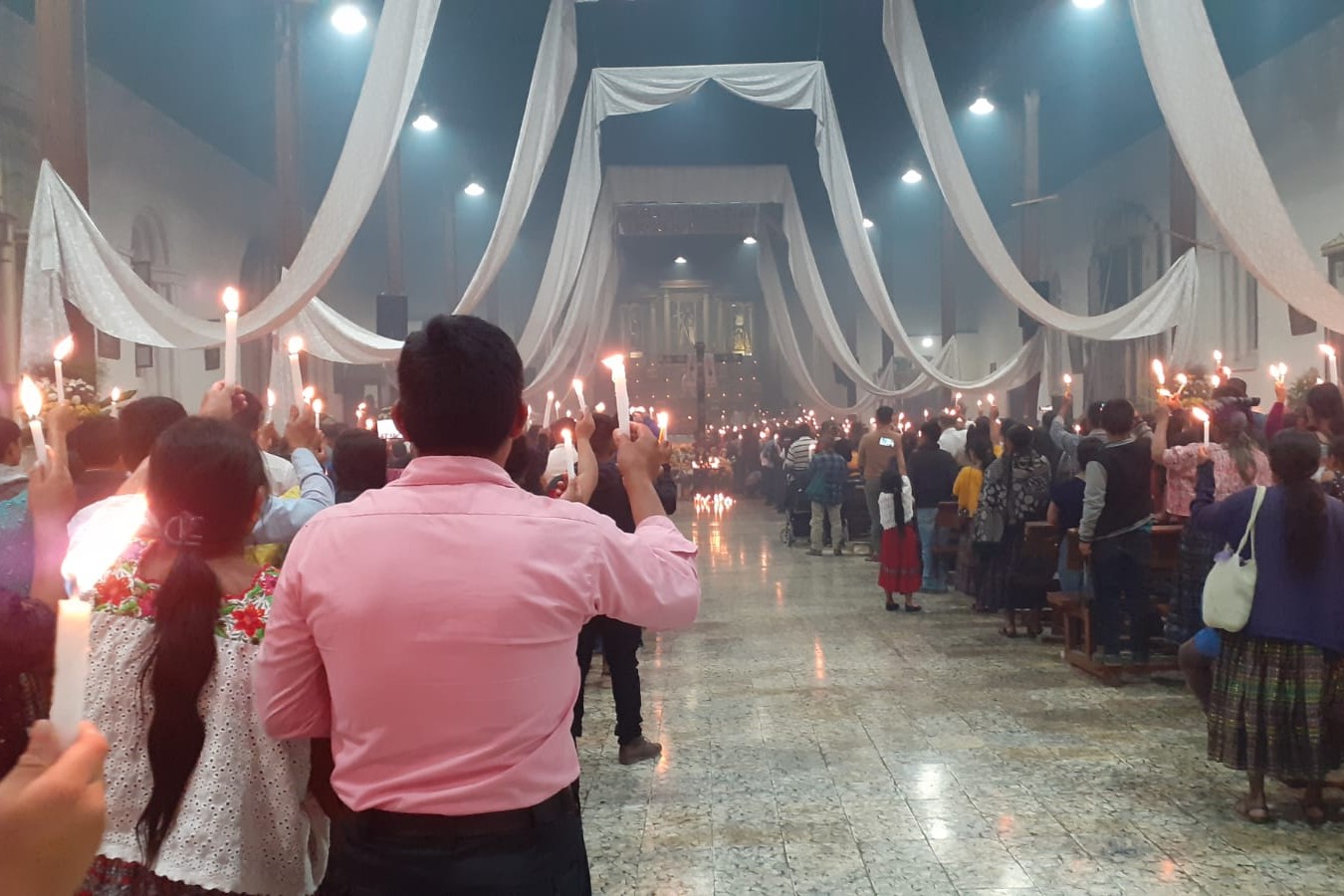 Personas sostienen velas encendidas durante una oración con la cruz maya junto a miembros de la parroquia, el 21 de abril de 2025, en Ciudad de Guatemala. (Foto: Hna. Dora Tupil)
