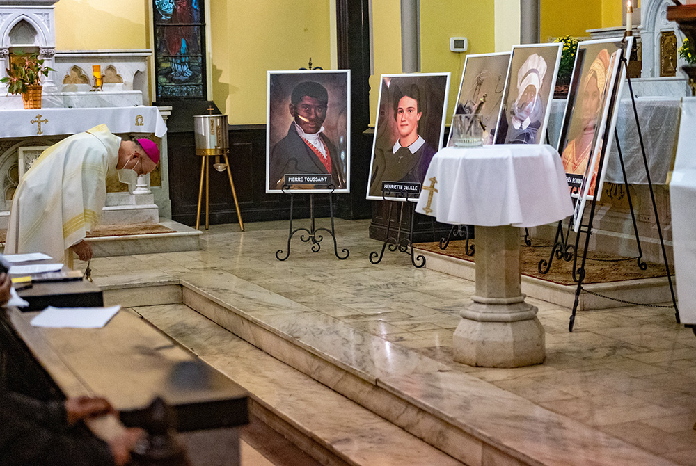 Baltimore Auxiliary Bishop Bruce Lewandowski bows before images of six African Americans who are candidates for sainthood during the All Saints' Day Mass at St. Ann Church Nov. 1 in Baltimore. (CNS/Catholic Review/Kevin J. Parks)