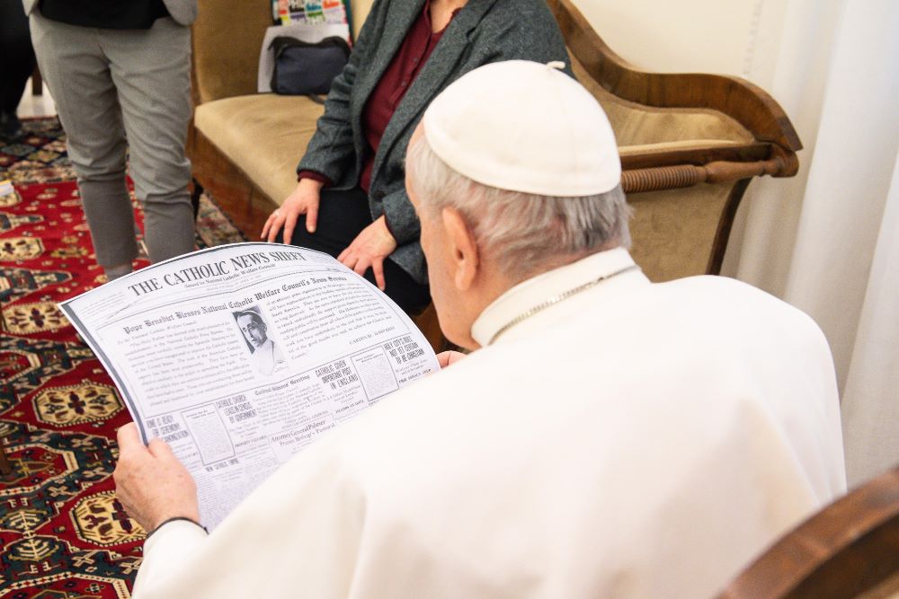 Pope Francis looks at a copy of the April 11, 1920, edition of the "Catholic News Sheet," during a meeting with members of the Catholic News Service Rome bureau at the Vatican Feb. 1, 2021. (CNS/Vatican Media)