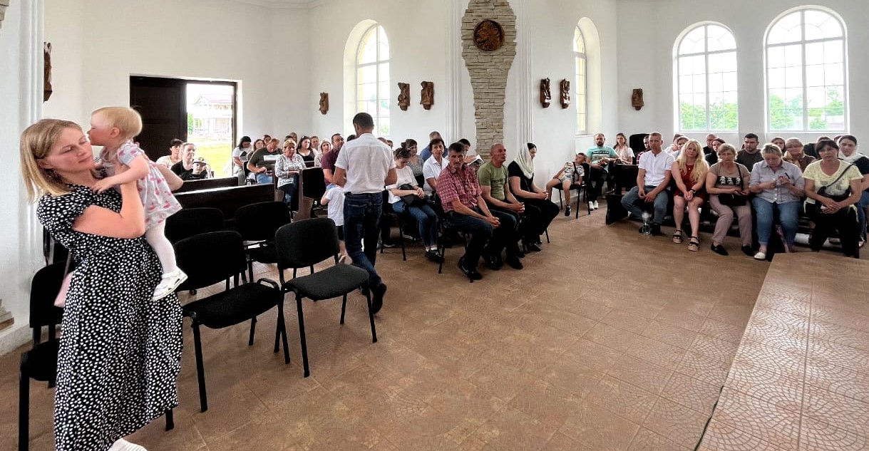 A mother and child walk into the prayer hall where people are seated for prayer and worship at St. Joseph of Saint-Marc Convent in Mukachevo, Ukraine. (Courtesy of Ligi Payyappilly)