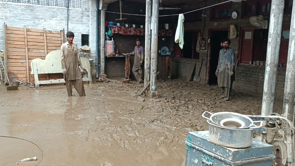 Mohammad Zahid (right) and his brothers look at his house in northern Pakistan's Swat Valley. "Within seconds, we were submerged in 4 to 5 feet of water," Zahid said. "I had to break the walls with a hammer to evacuate the family." (Amjad Gulzar)