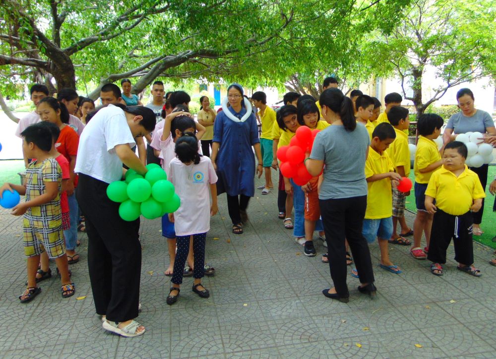 Lovers of the Holy Cross of Huế Sr. Maria Truong Thi Bich Thao (center) and other volunteers lead 60 children who are hearing-impaired and mute to play a balloon game at their convent in Hue Sept. 7. (GSR photo/Joachim Pham)