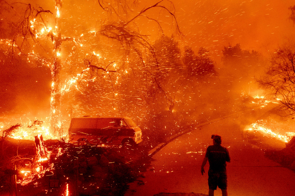 Bruce McDougal watches embers fly over his property as the Bond Fire burns through the Silverado community in Orange County, California, on Dec. 3, 2020. (AP/Noah Berger)