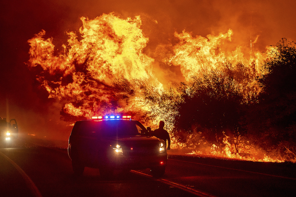 Flames lick above vehicles on Highway 162 as the Bear Fire burns in Oroville, California, on Sept. 9, 2020. The blaze, part of the lightning-sparked North Complex, expanded rapidly as winds buffeted the region. (AP Photo/Noah Berger)