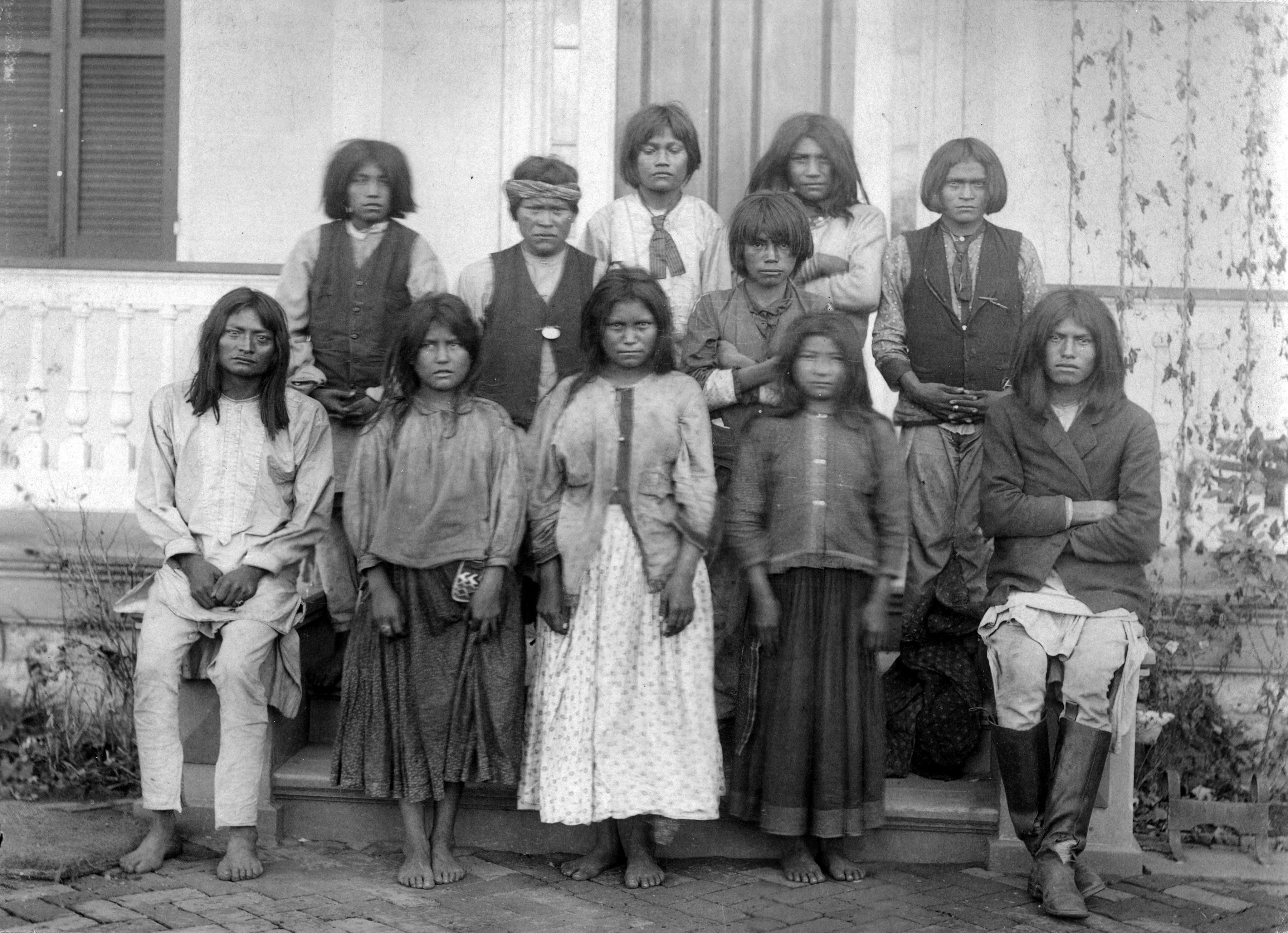 Native American (Chiricahua Apache) boys and girls pose outdoors at the Carlisle Indian Industrial School in Carlisle, Pennsylvania, after their arrival from Fort Marion, Florida, in November 1886. Photo by J. N. Choate/Creative Commons