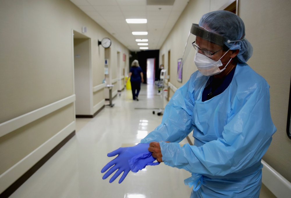 Registered nurse Kevin Hoover puts on protective gear as he prepares to check on a COVID-19 patient May 20 at the rural 24-bed Kearny County Hospital in Lakin, Kansas. The county has seen a spike in cases due to clusters in nearby meatpacking plants. (AP) Registered nurse Kevin Hoover puts on protective gear as he prepares to check on a COVID-19 patient May 20 at the rural 24-bed Kearny County Hospital in Lakin, Kansas. The county has seen a spike in cases due to clusters in nearby meatpacking plants. (AP)