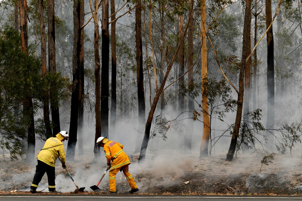 Firefighters contain a bushfire along a highway near Ulladulla, Australia, Jan. 5. (CNS/Reuters/AAP/Dean Lewins) Firefighters contain a bushfire along a highway near Ulladulla, Australia, Jan. 5. (CNS/Reuters/AAP/Dean Lewins)