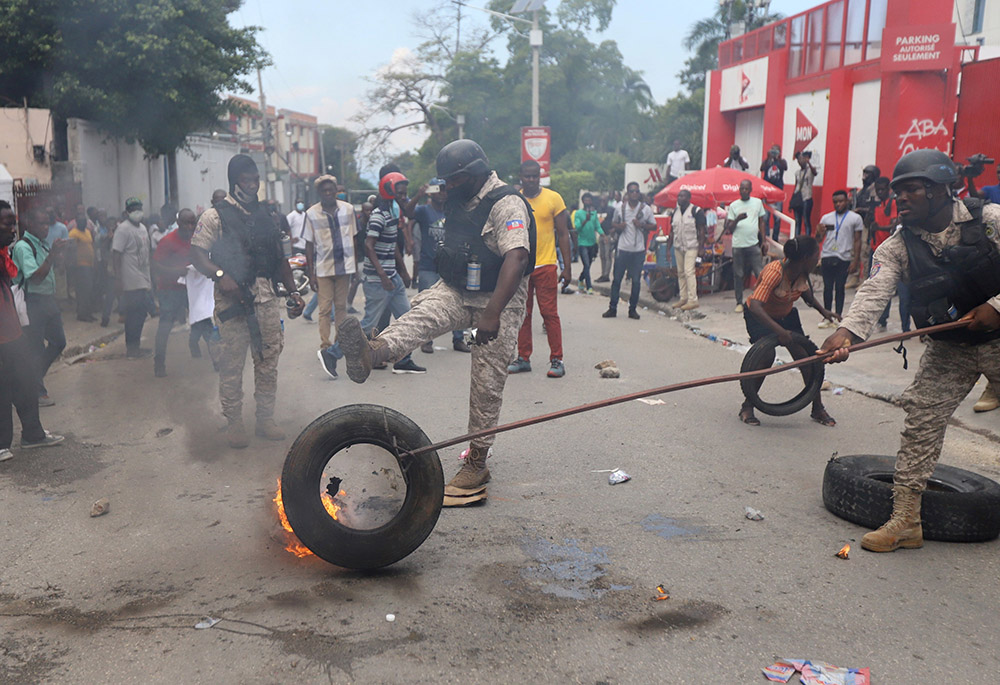 Police in Port-au-Prince, Haiti, remove a burning tire Oct. 18, 2021, as people mount a nationwide strike to protest a growing wave of kidnappings. (CNS/Reuters/Ralph Tedy Erol)