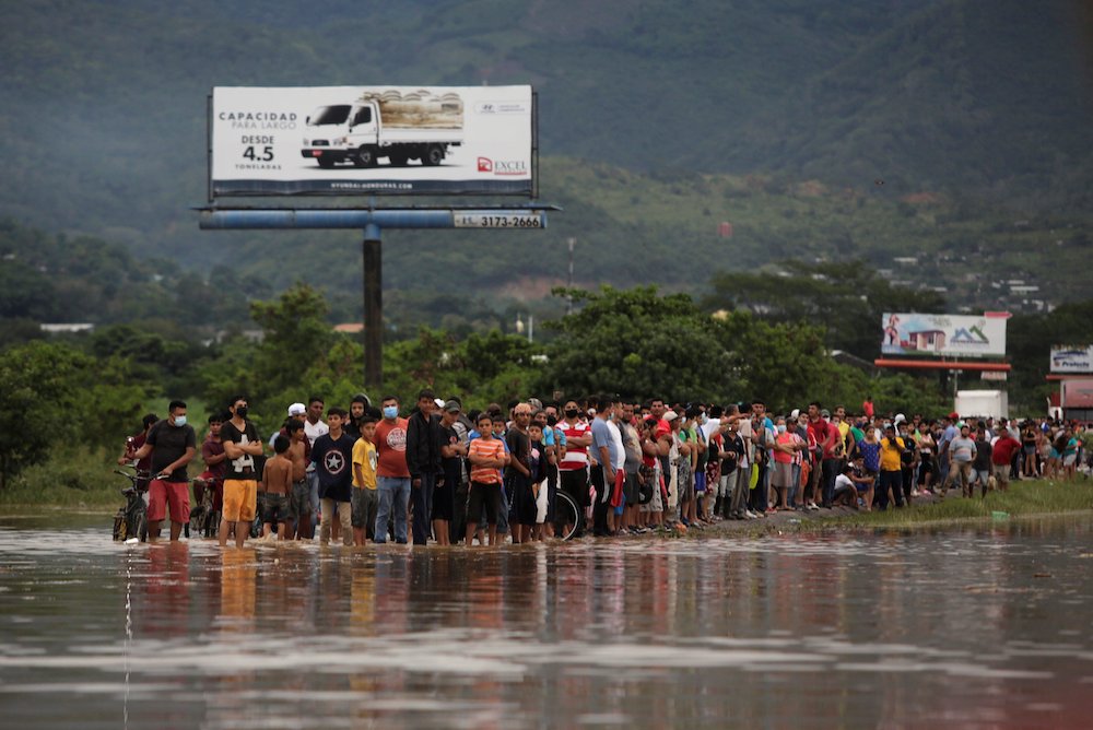 People stand alongside floodwaters in La Lima, Honduras, Nov. 5, in the remains of Hurricane Eta. (CNS/Reuters/Jorge Cabrera)