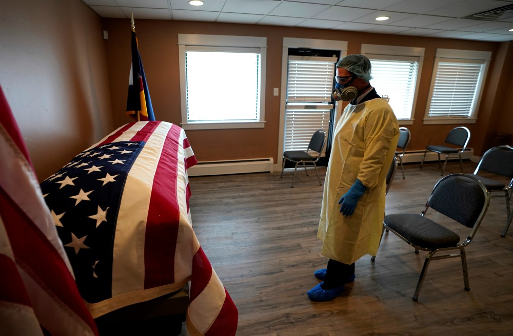 On April 23, Michael Neel, funeral director of All Veterans Funeral and Cremation in Denver, looks at the casket of George Trefren, a 90-year-old Korean War veteran who died of the coronavirus in a nursing home. (CNS / Reuters / Rick Wilking)