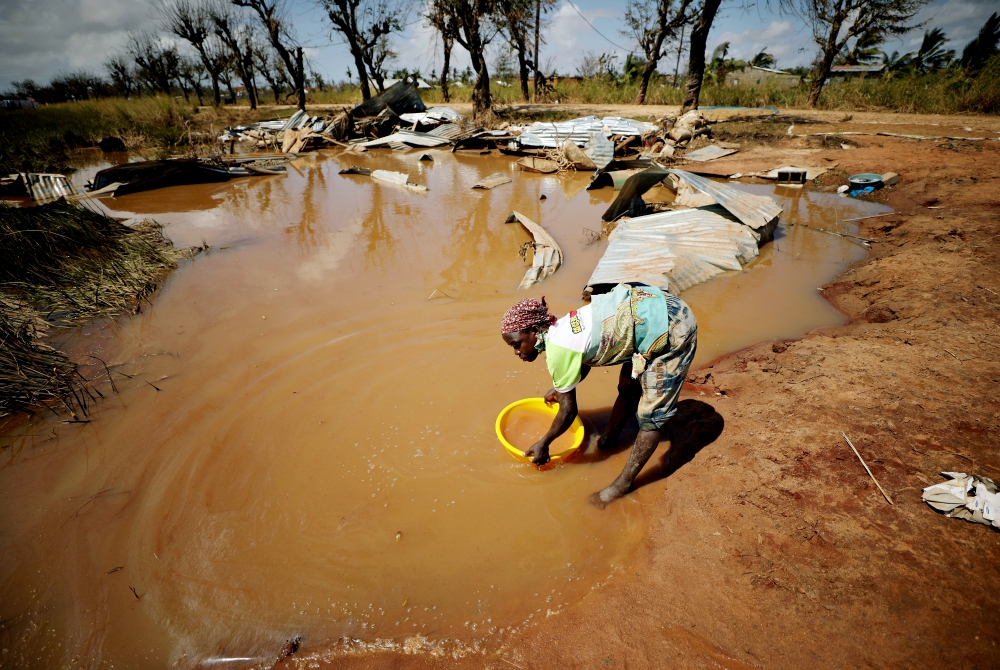 A woman collects water for washing as floodwaters begin to recede in the aftermath of Cyclone Idai near Beira, Mozambique, in March. (CNS/Reuters/Mike Hutchings)