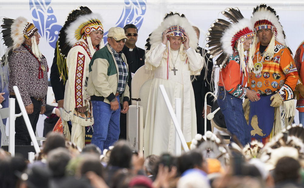 Pope Francis dons a headdress during a visit with Indigenous peoples at Maskwaci, the former Ermineskin Residential School, Monday, July 25, 2022, in Maskwacis, Alberta. (AP Photo/Eric Gay)