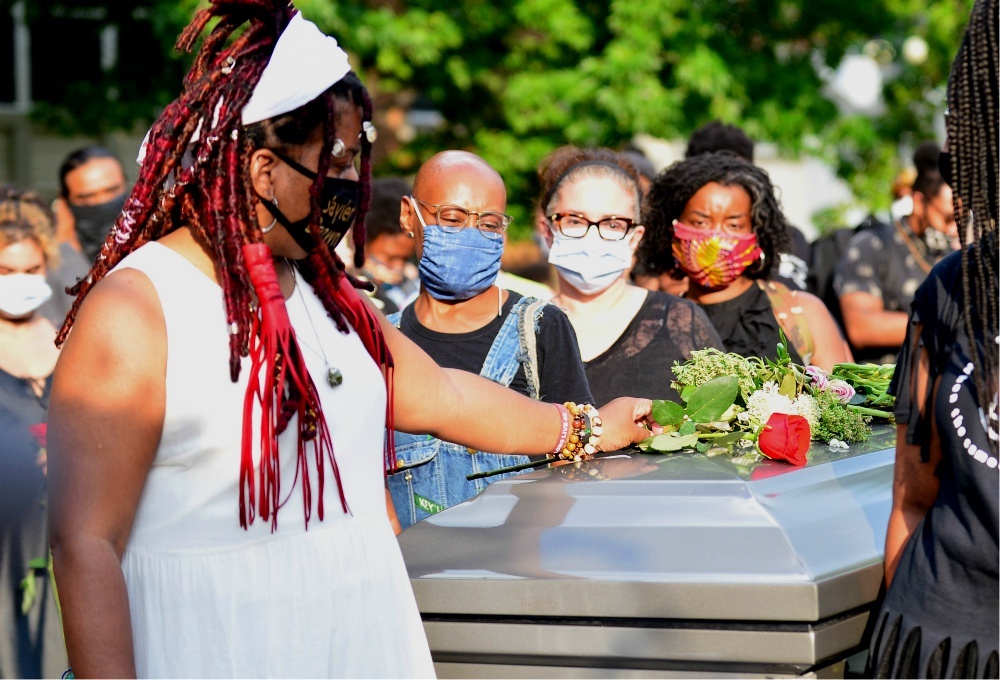 Dannielle Brown places flowers on an empty casket during her "living funeral" in Pittsburgh on Aug. 6, more than a month into her hunger strike. Brown told NCR on Aug. 31 that she is not sure she will survive her strike, and that she wants to be remembere Dannielle Brown places flowers on an empty casket during her "living funeral" in Pittsburgh on Aug. 6, more than a month into her hunger strike. Brown told NCR on Aug. 31 that she is not sure she will survive her strike, and that she wants to be remembere