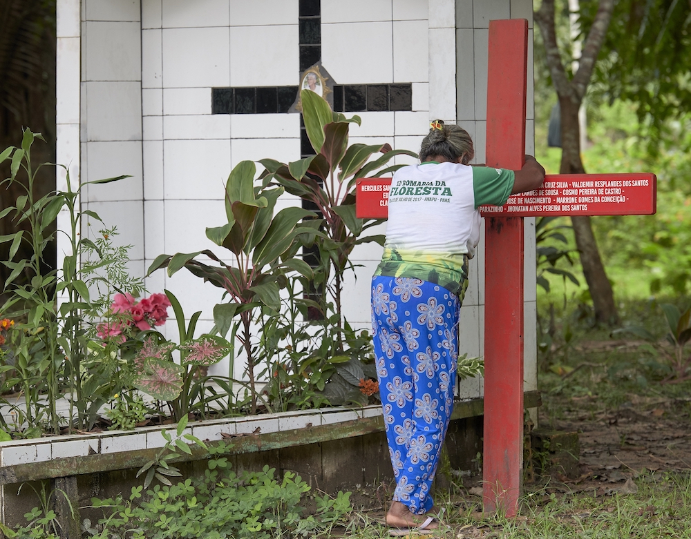 Antonia Silva Lima prays at the grave of U.S.-born Sister Dorothy Stang in Brazil. The red cross bears the names of local rights activists murdered since her killing. (CNS Photo/Paul Jeffrey)