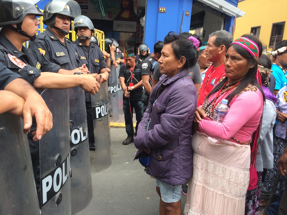 Indigenous women protesting oil pollution in the Peruvian Amazon face off with police outside the Congress building in Lima in 2016. (Barbara Fraser)