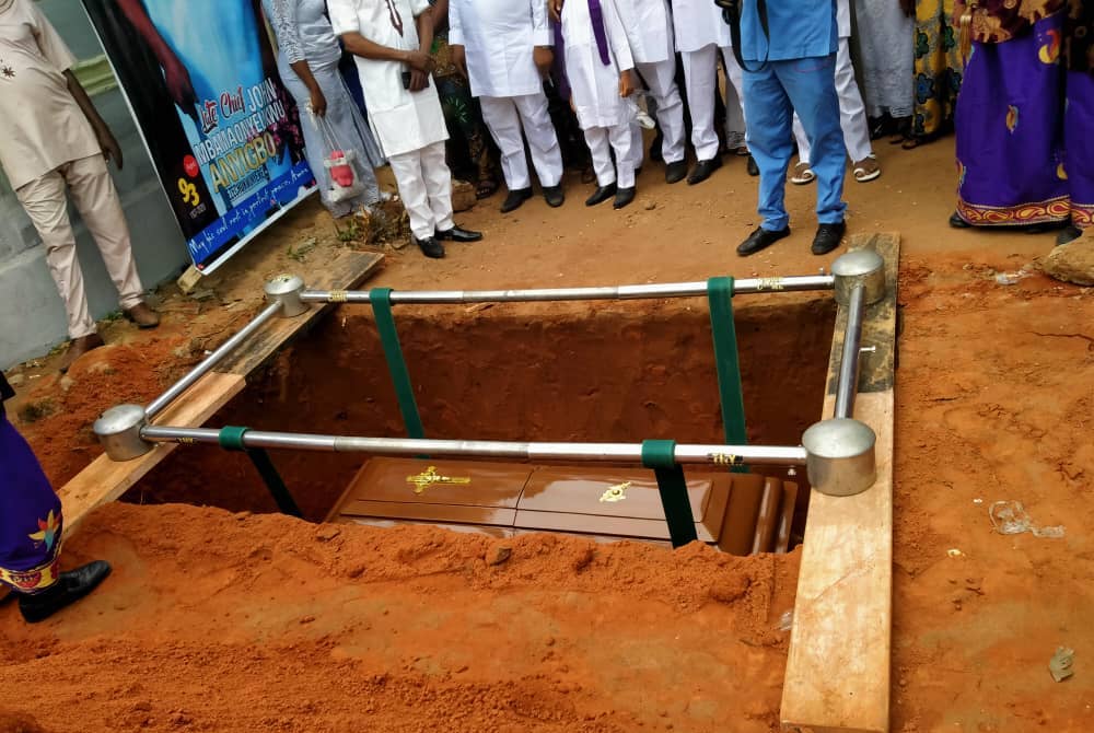 Paschal Anyibgo's family surrounds the casket of their patriarch, John, during his interment. (Provided photo)