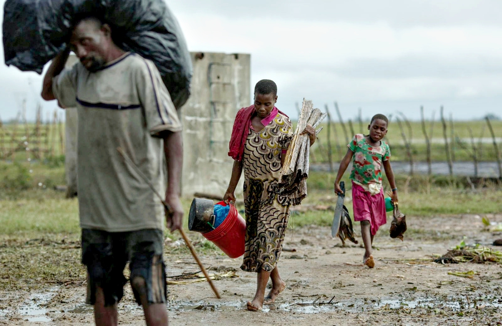 People affected by Cyclone Idai walk with their belongings in Beira, Mozambique. (CNS / Care International via Reuters / Josh Estey)