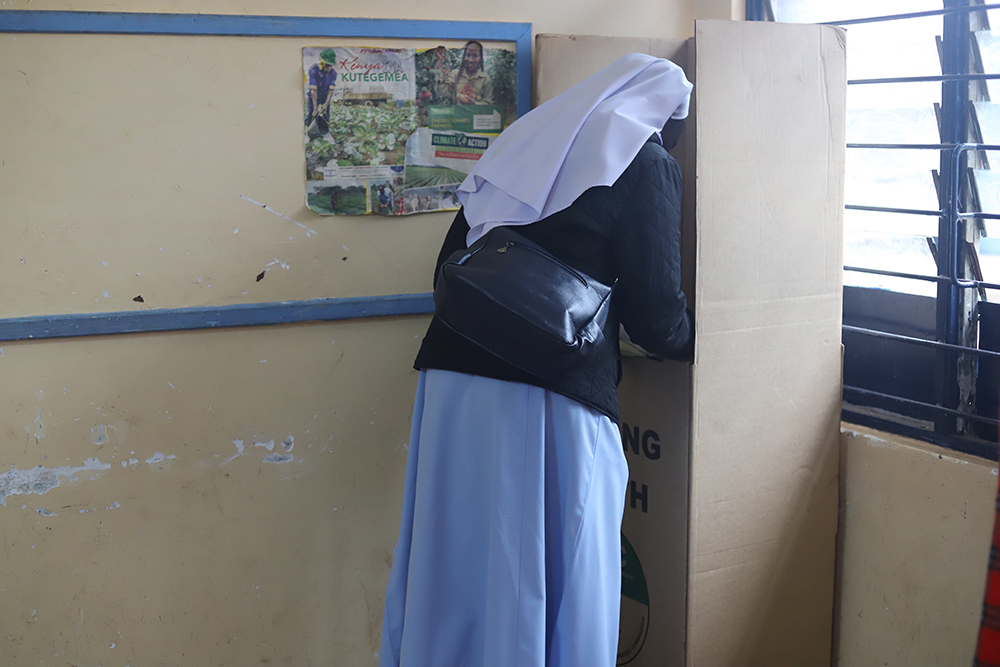 A religious sister marks her ballot paper at the Milimani Primary School polling station Aug. 9 in Nairobi, Kenya. Religious sisters are among millions of Kenyans voting for a president, governors, senators, members of the national assembly and local coun