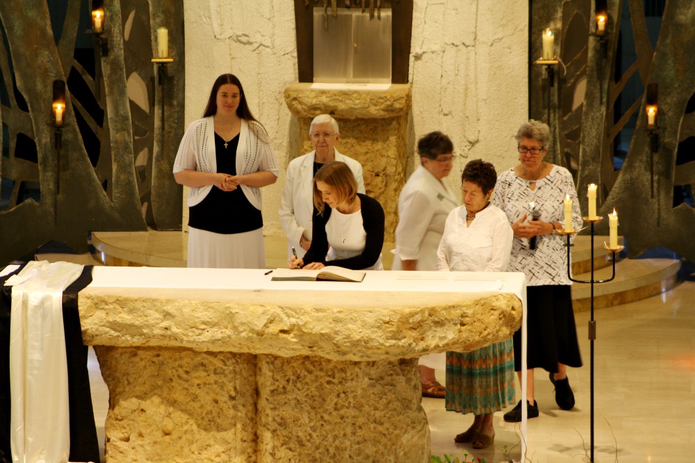 Sr. Quincy Howard signs her profession documents July 30, 2017. Behind her are, from left: Sr. Nicole Reich, Sr. Rosanna Gleason, Sr. Toni Harris, Sr. Jo Ann Timmerman and Sr. Mary Ann Nelson. (Courtesy of the Dominicans of Sinsinawa)