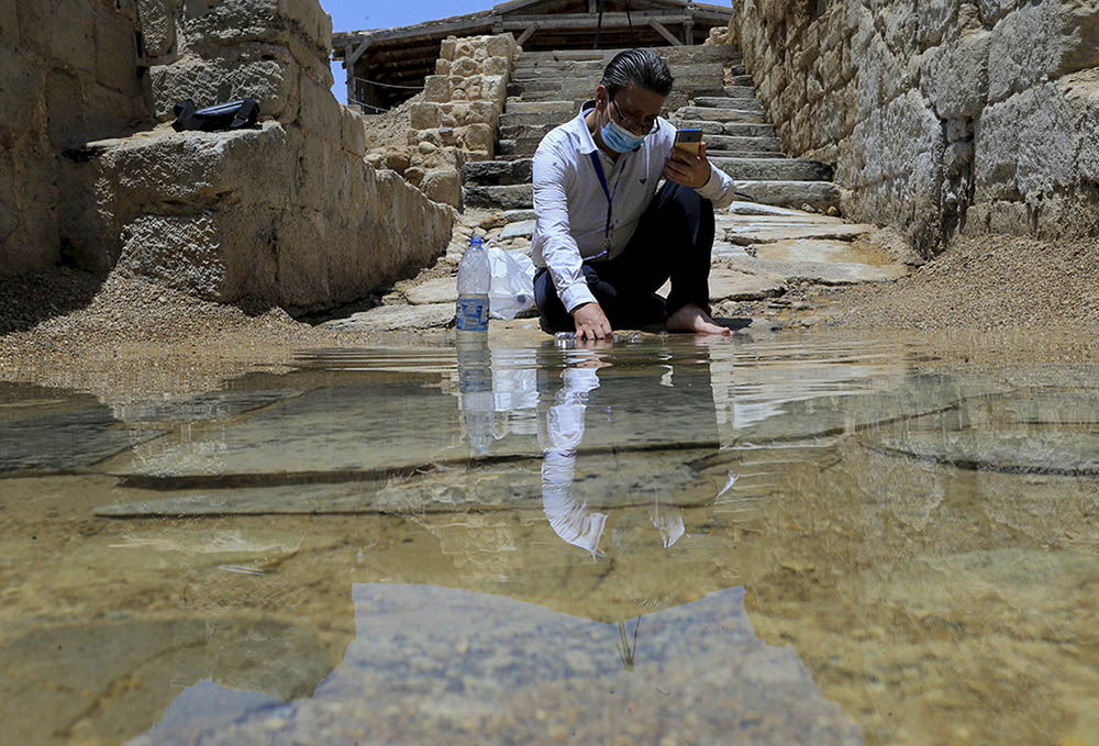 Syrian Christian Zuhair Al-Sahawi immerses his hand in water at the Bethany Beyond the Jordan baptismal site on the east bank of the Jordan River in Jordan June 8. (AP/Raad Adayleh)