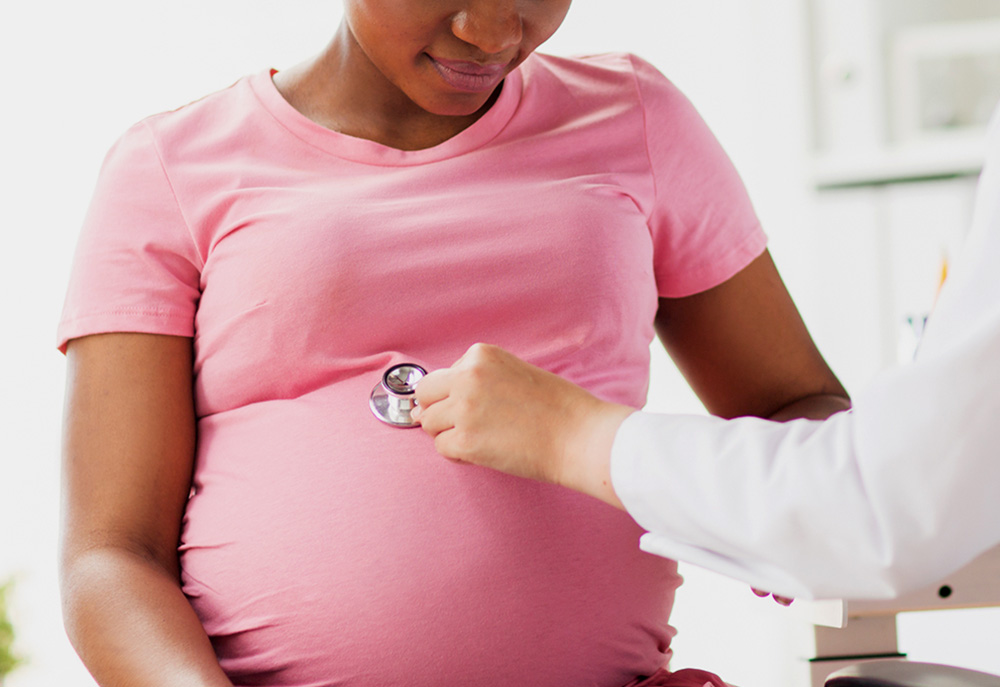 Pregnant Black woman seeing a doctor (Dreamstime/Syda Productions)