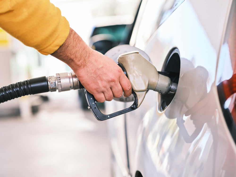 Person putting gasoline into car with nozzle. (Unsplash/Engin Akyurt)