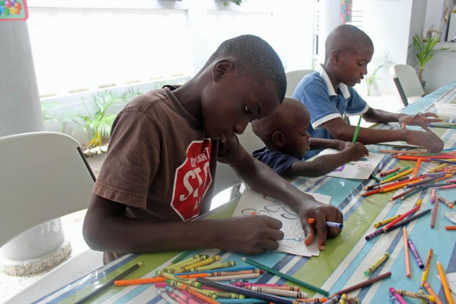 Children draw with crayons in a church-run shelter.