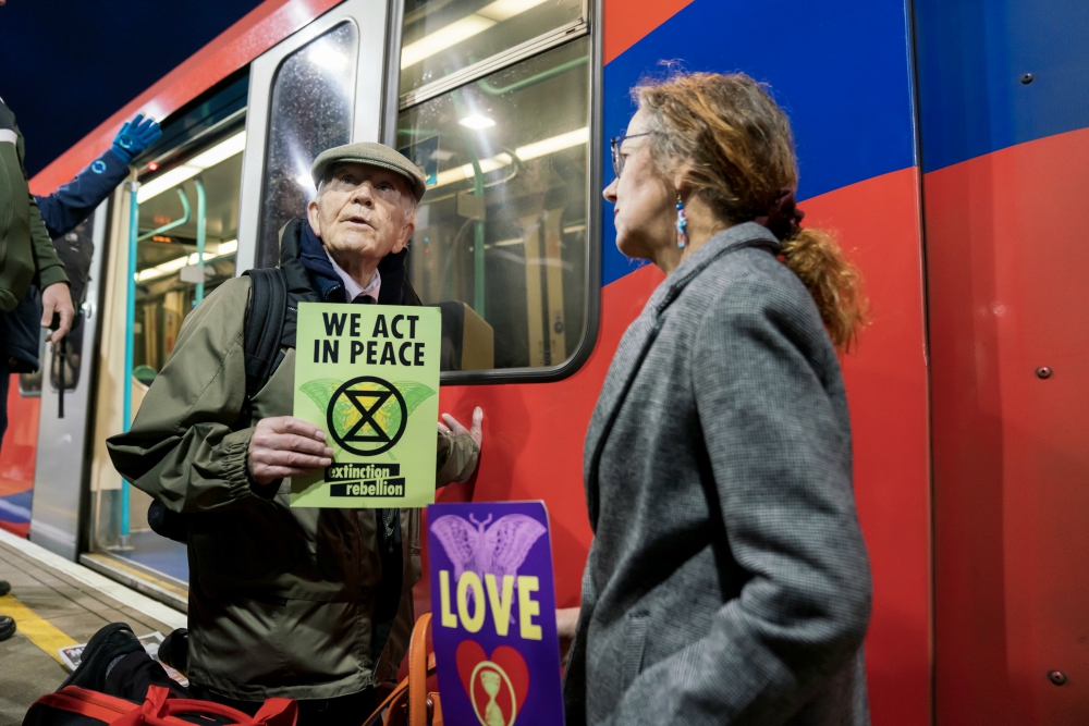 Phil Kingston, 83, a former parole officer, protests climate change after super-gluing himself to the side of a train on the platform at London's Shadwell Station Oct. 17. (Courtesy of Extinction Rebellion/ Vladimir Morozov)