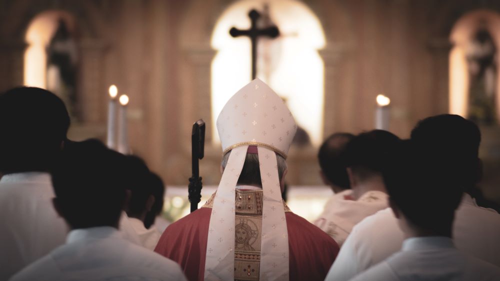 the back of a bishop, flanked by altar servers, in a procession