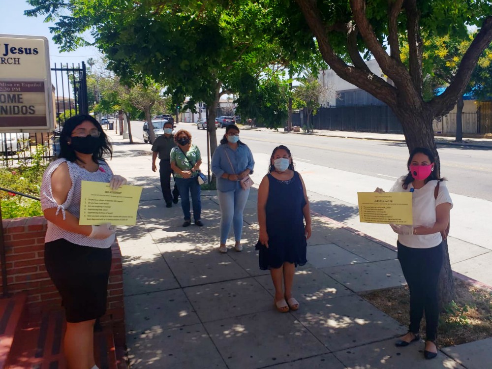 Visitors wait outside to attend 12:30 p.m. Spanish Mass, while volunteers display symptom screening questions. (Courtesy of Fr. Kenneth Ugwu)