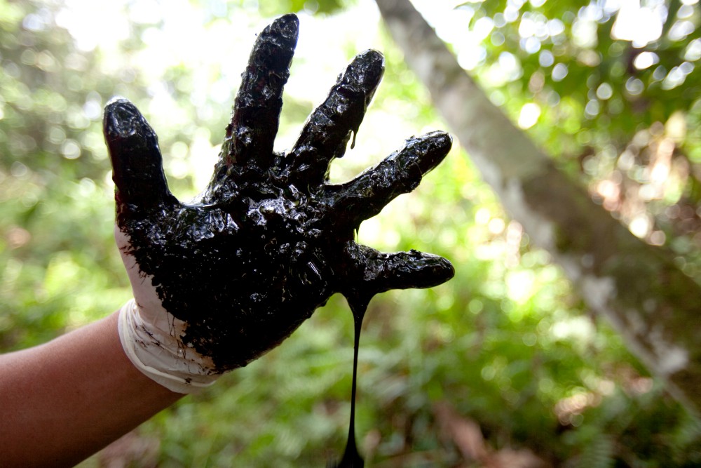 Local community members show crude oil contamination left behind in open oil pits never remediated by U.S. oil companies in Lago Agrio in Ecuador in May 2019. (Stand.earth via Reuters/Tyson Miller)