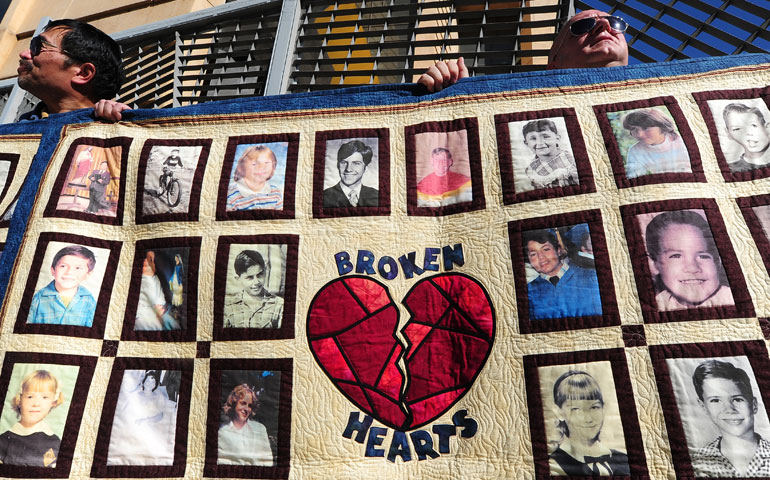 Abuse victim Jorgen Olsen, right, and supporter Glenn Gorospa hold quilts bearing portraits of abused children while gathered outside the Cathedral of Our Lady of the Angels in Los Angeles Feb. 1. (AFP PHOTO/Frederic J. BROWN)