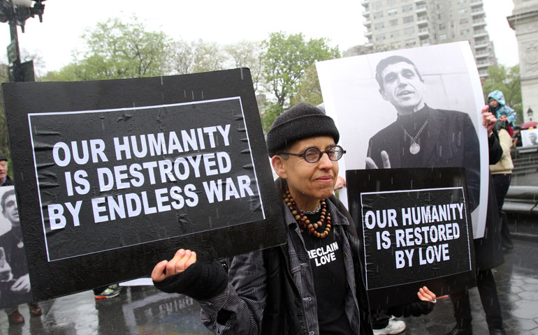 A mourner carries signs as she participates in a peace march May 6 prior to the funeral Mass of Jesuit Fr. Daniel Berrigan at the Church of St. Francis Xavier in New York City. (CNS/Gregory A. Shemitz)