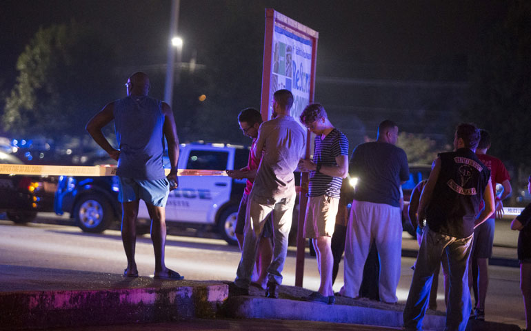 Bystanders watch over the scene at a movie theater where a man opened fire on filmgoers in Lafayette, La., July 23. (Newscom/Reuters/Lee Celano)