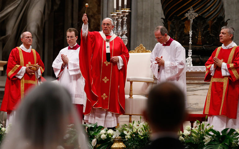 Pope Francis blesses new spouses with holy water while celebrating the marriage rite for 20 couples during a Mass in St. Peter's Basilica at the Vatican Sept. 14.