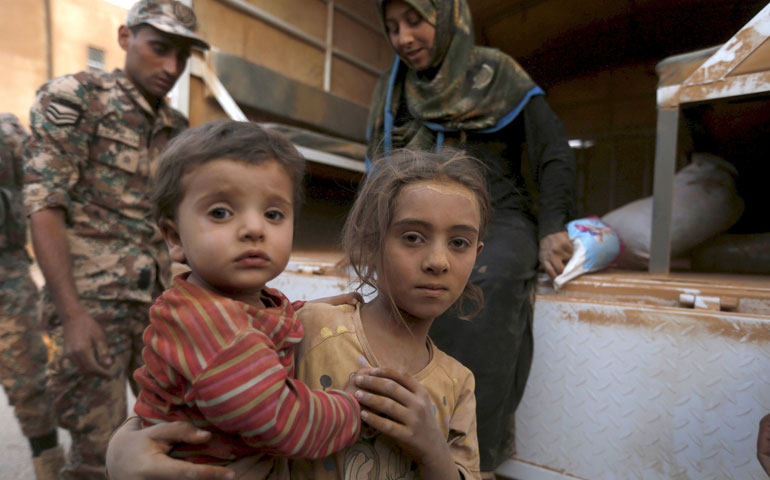 Syrian refugee children covered with dust arrive Sept. 10 at the Jordanian border with Syria and Iraq, near the town of Ruwaished (CNS/Reuters/Muhammad Hamed)