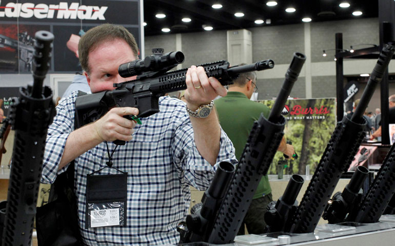 A man looks through a rifle scope in late May at the National Rifle Association's Annual Meetings & Exhibits show in Louisville, Ky. (CNS/Reuters/John Sommers II)