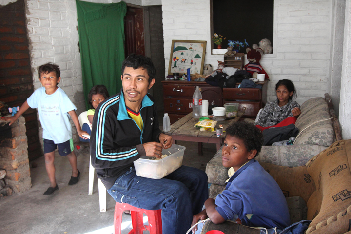 Ricardo Lemos, 28, shreds cooked chicken for sandwiches his wife sells daily in Quito, Ecuador. The family fled violence in Colombia. (CNS/Barbara Fraser)