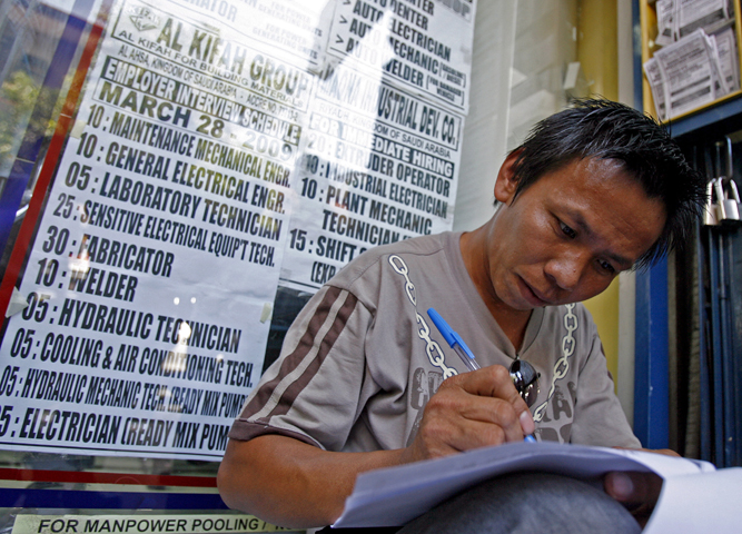In this 2009 file photo, a Filipino jobseeker fills out forms outside a recruitment agency in Manila for jobs in the Middle East. (CNS/Alanah Torralba, EPA)