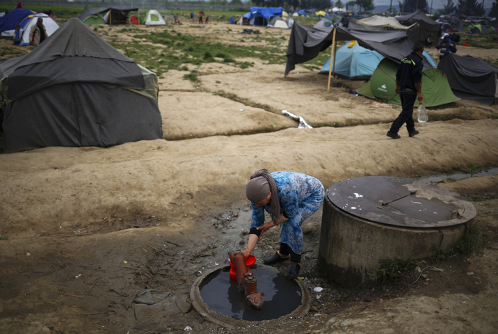 A woman collects water at a makeshift camp for migrants and refugees at the Greek-Macedonian border near the village of Idomeni, Greece. (CNS/Stoyan Nenov, Reuters)