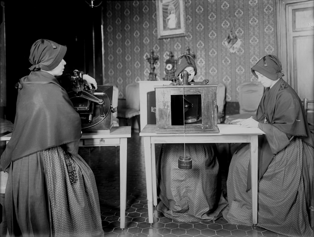 Members of the Sisters of the Child Mary use microscopes to review glass plates as they measure star positions. (CNS/Vatican Observatory)