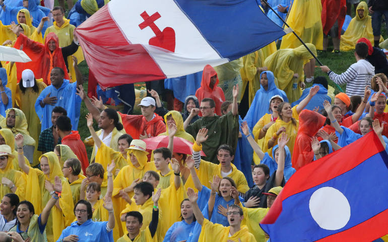 Pilgrims sing and dance in the rain prior to the opening Mass for World Youth Day July 26 at Blonia Park in Krakow, Poland. (CNS photo/Bob Roller)