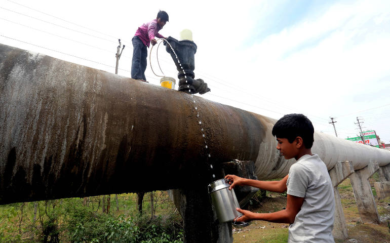 Indian boys collect drinking water in early May from the main water supply line in Bhopa. (CNS photo/Sanjeev Gupta, EPA)
