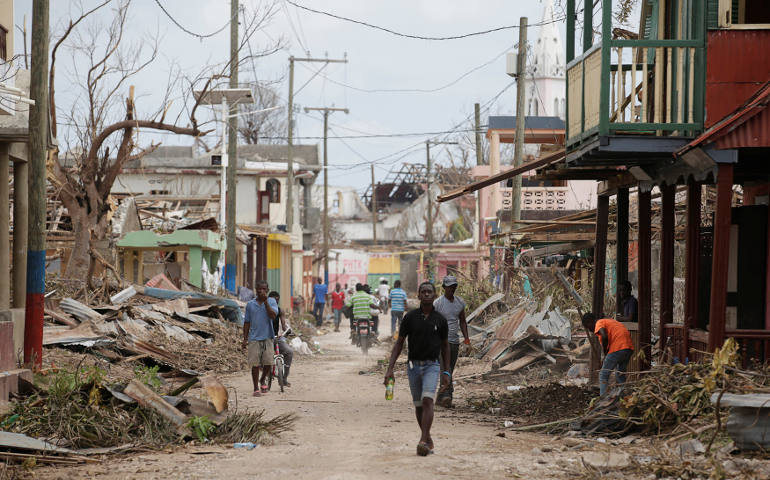 People walk past damaged buildings Oct. 9 after Hurricane Matthew swept through Port-a-Piment, Haiti. (CNS photo/Andres Martinez Casares, Reuters)