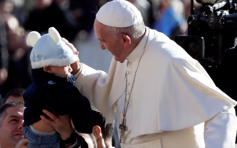 Pope Francis blesses a child as he arrives to lead his Nov. 9 general audience in St. Peter's Square at the Vatican. (CNS/Reuters/Stefano Rellandini)