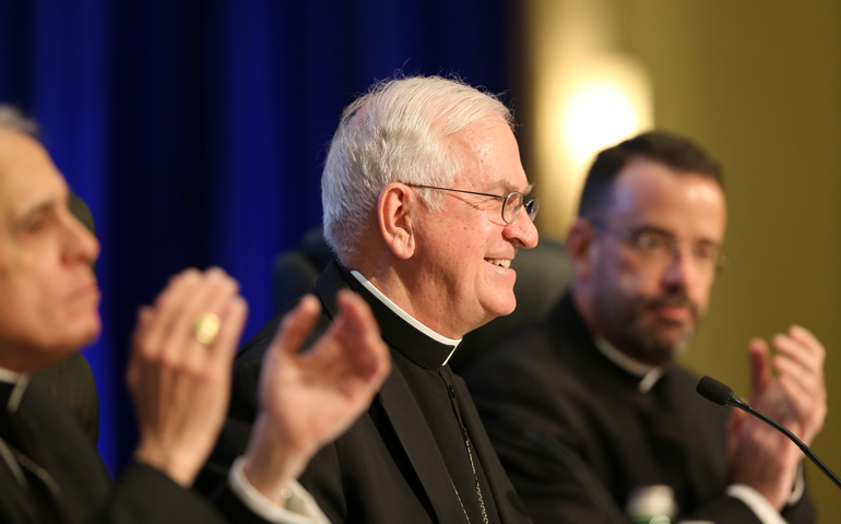 Cardinal Daniel DiNardo, and Msgr. J. Brian Bransfield, right, applaud Nov.. 14 as Archbishop Joseph Kurtz smiles during the bishops' fall eneral assembly in Baltimore. (CNS/Bob Roller)