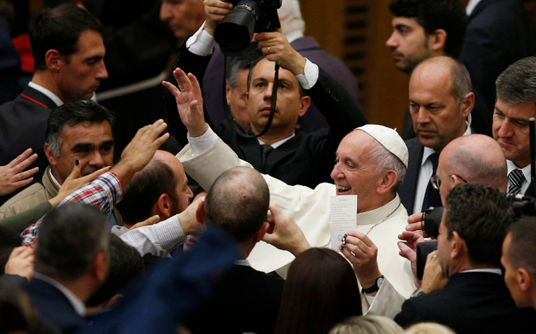 Pope Francis holds a prayer card as he greets the crowd during his general audience in Paul VI hall at the Vatican Nov. 23. (CNS / Paul Haring)