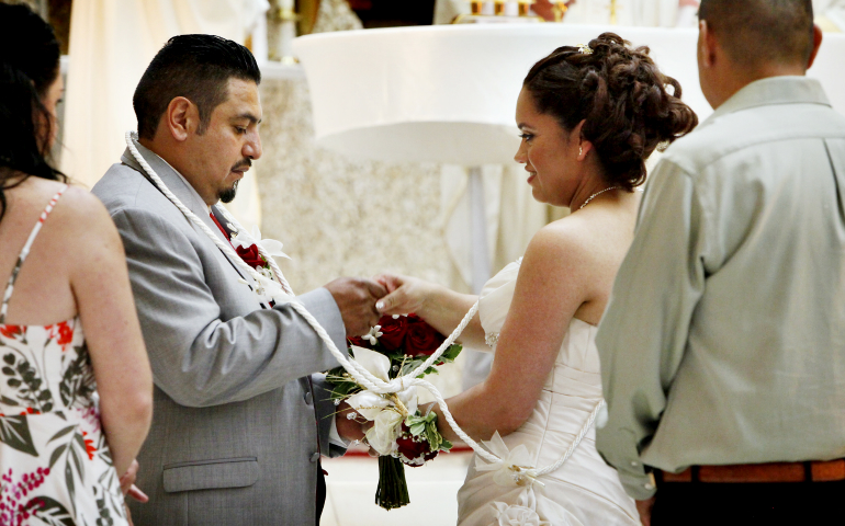 A bride and groom hold hands during a marriage convalidation Mass in 2016 at Immaculate Conception Church in Chicago. Couples married civilly take part in such services to receive the sacrament of matrimony. (CNS/Chicago Catholic/Karen Callaway)