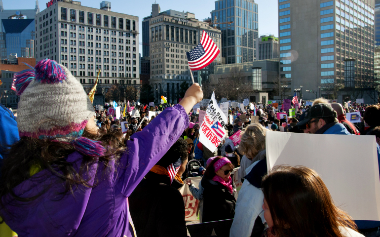 A girl waves a U.S. flag as thousands gather outside to protest President Donald Trump's speech March 15 at the Nashville Municipal Auditorium in Tennessee. (CNS/Tennessee Register/Theresa Laurence)