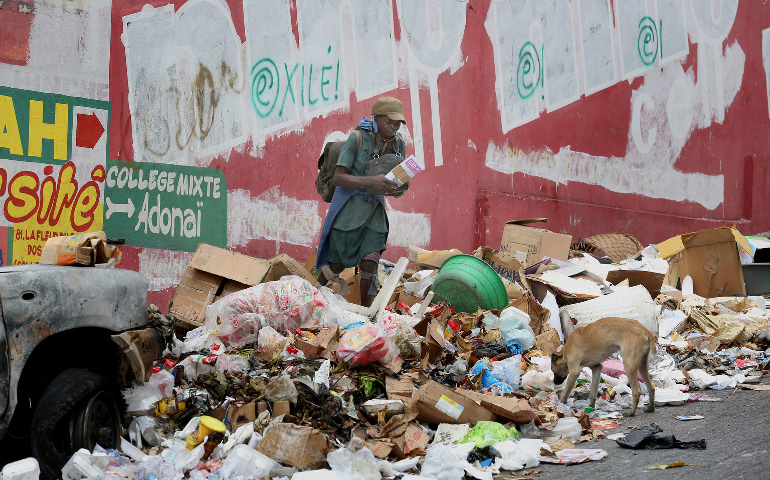 A woman and dog are seen amid garbage along a street in 2015 in Port-au-Prince, Haiti. Blessed Paul VI's 1967 encyclical "Populorum Progressio" rooted the Catholic Church in solidarity with the world's poorest nations. (CNS/Bob Roller)